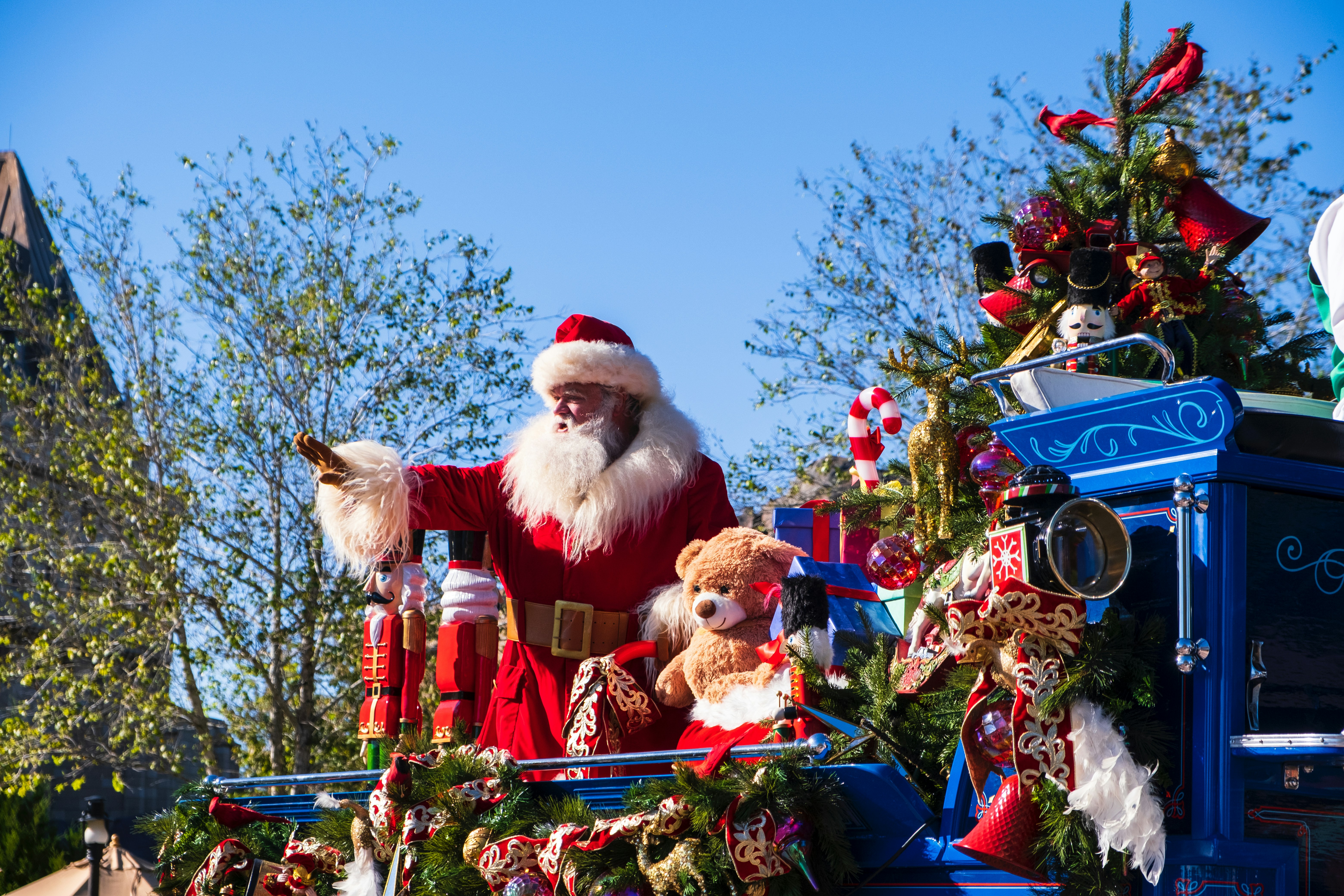 Santa Claus waving from a red and blue float during a holiday parade