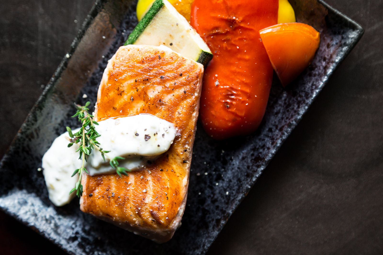A salmon fillet served on top of roasted vegetables