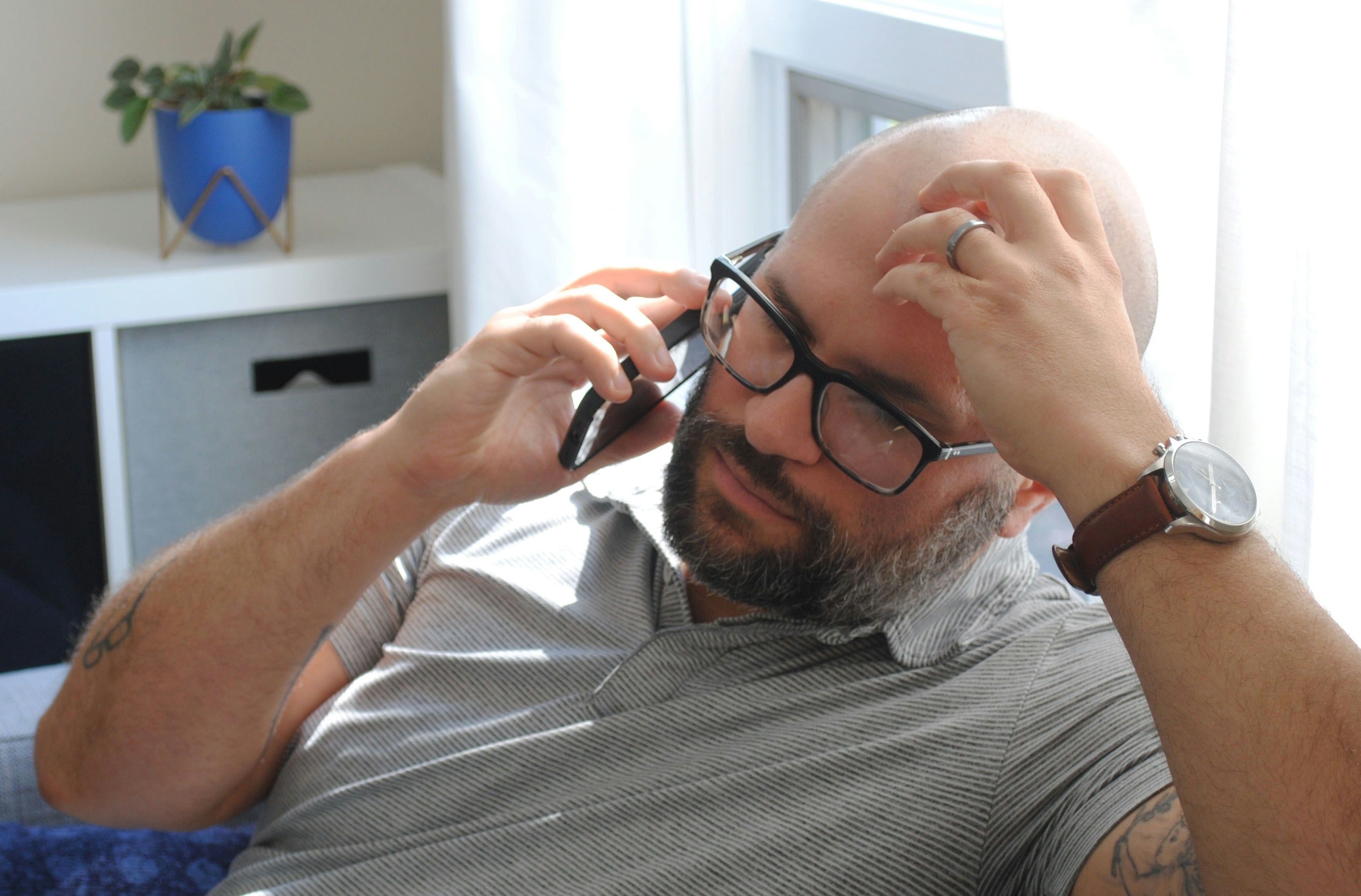 A man with glasses talking on a cell phone and looking concerned